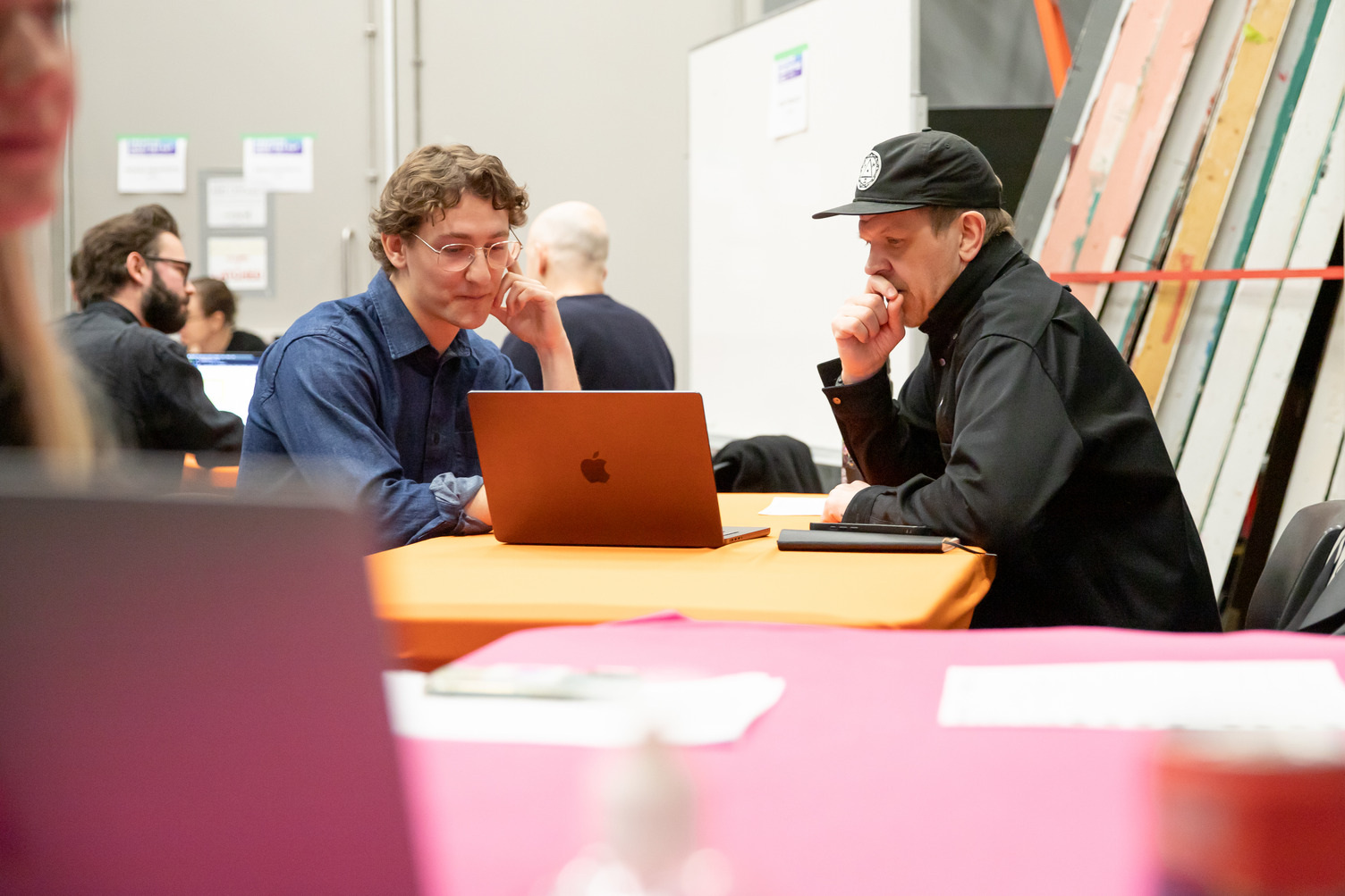 A student and industry lead chat at a table with a pink tablecloth