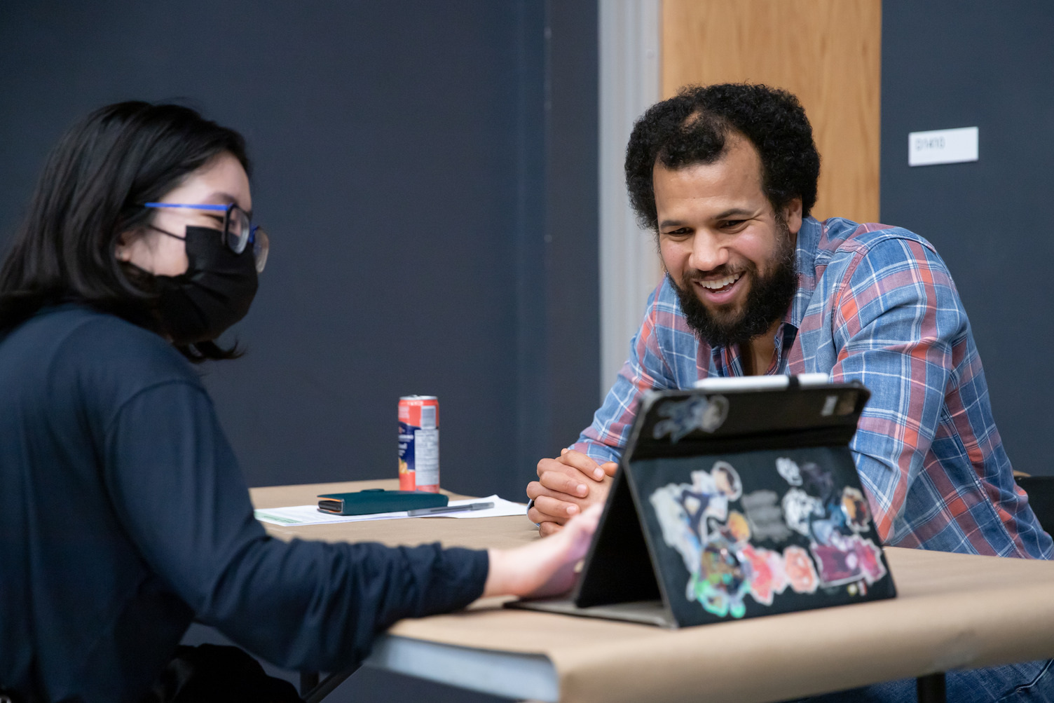 A student and industry lead look at an iPad at a wooden table