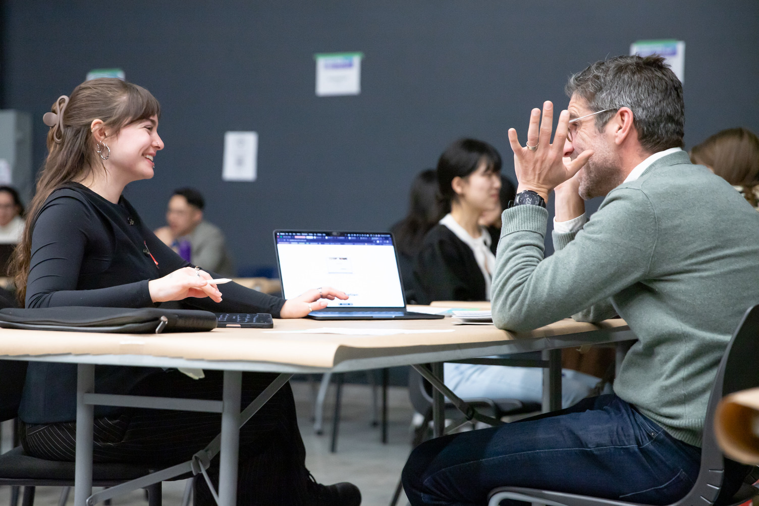 A student and industry lead chat and a laptop is in the foreground