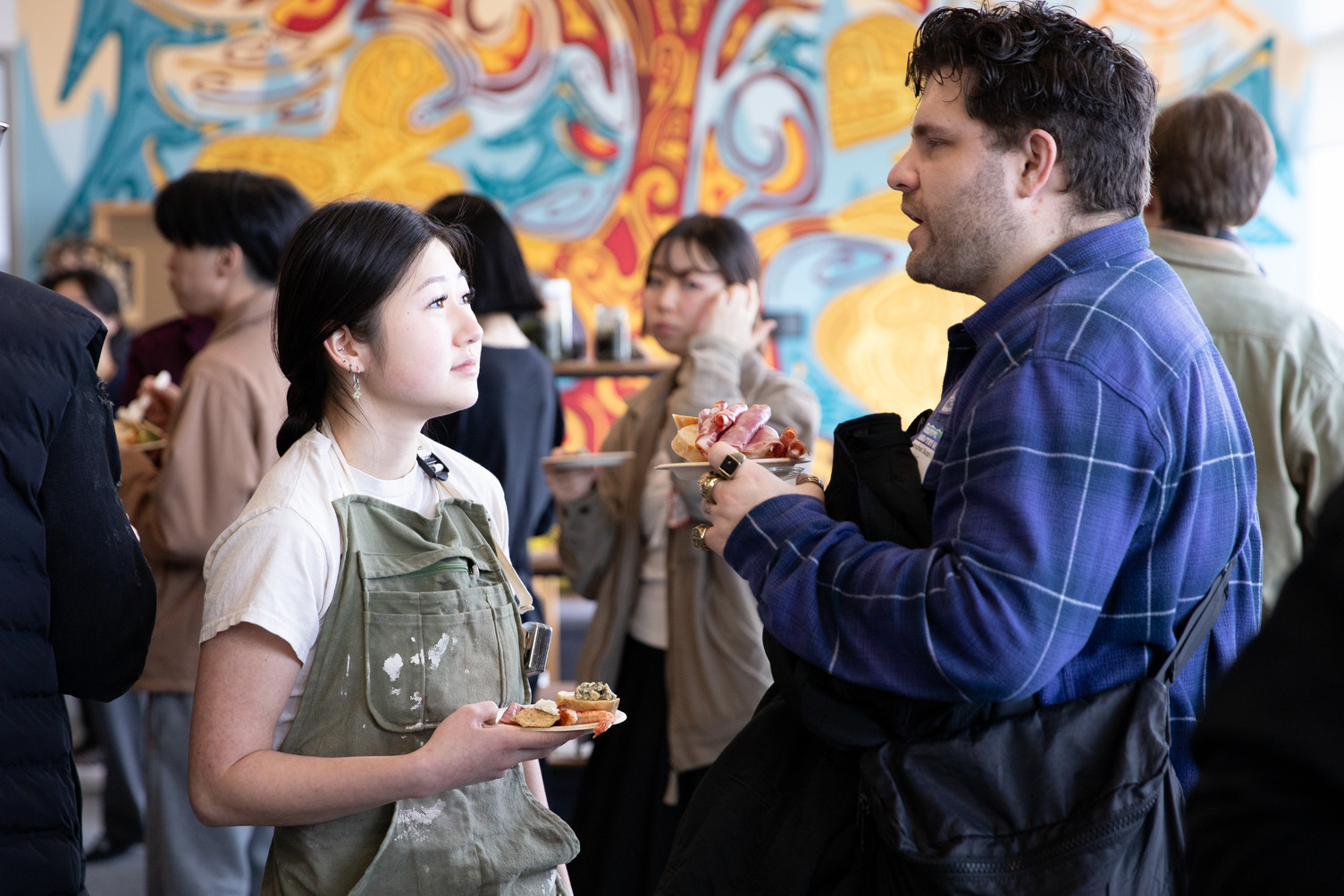 A student and industry lead chat against a colourful background at a mixer