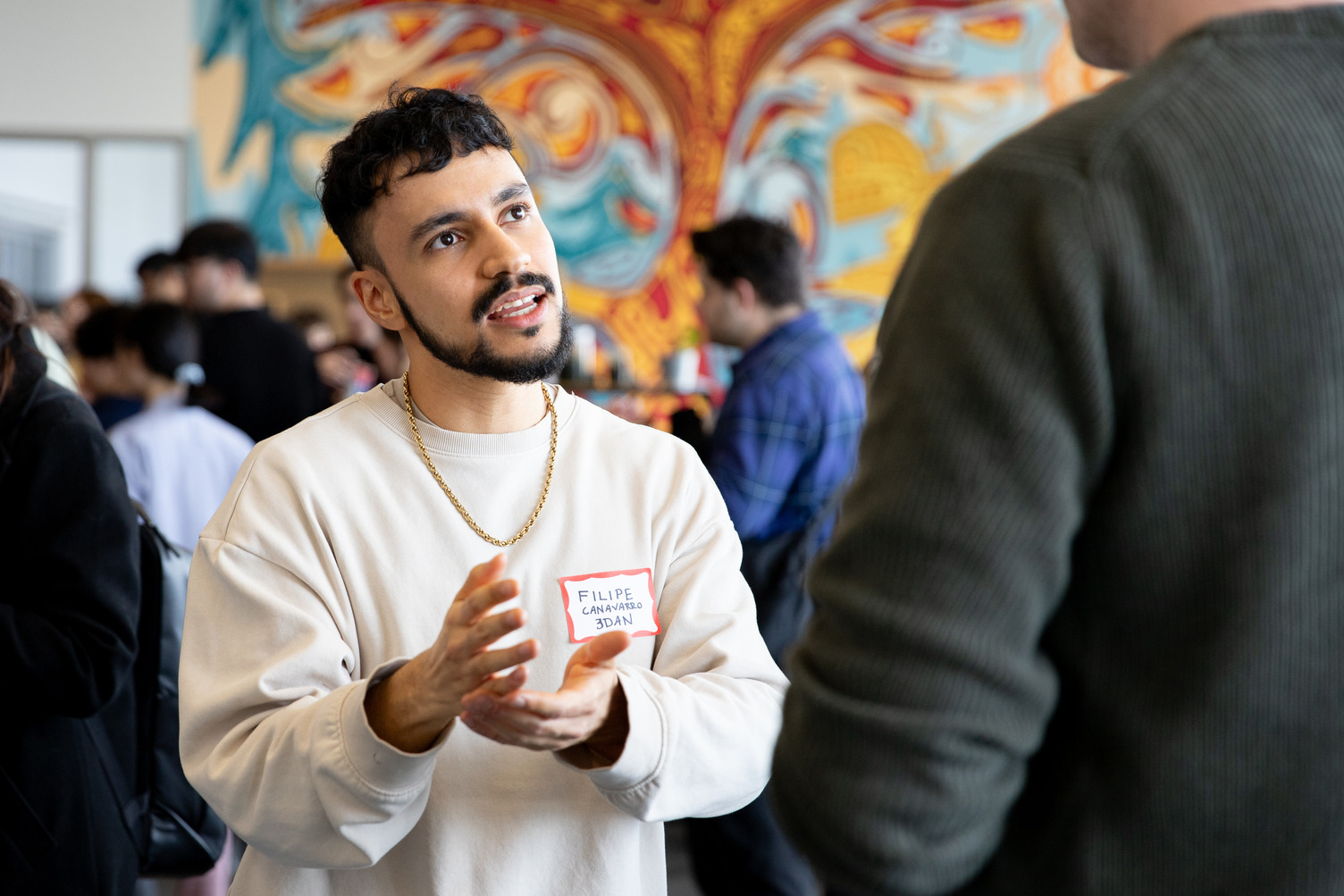 A student is using their hands animatedly to explain something at a mixer