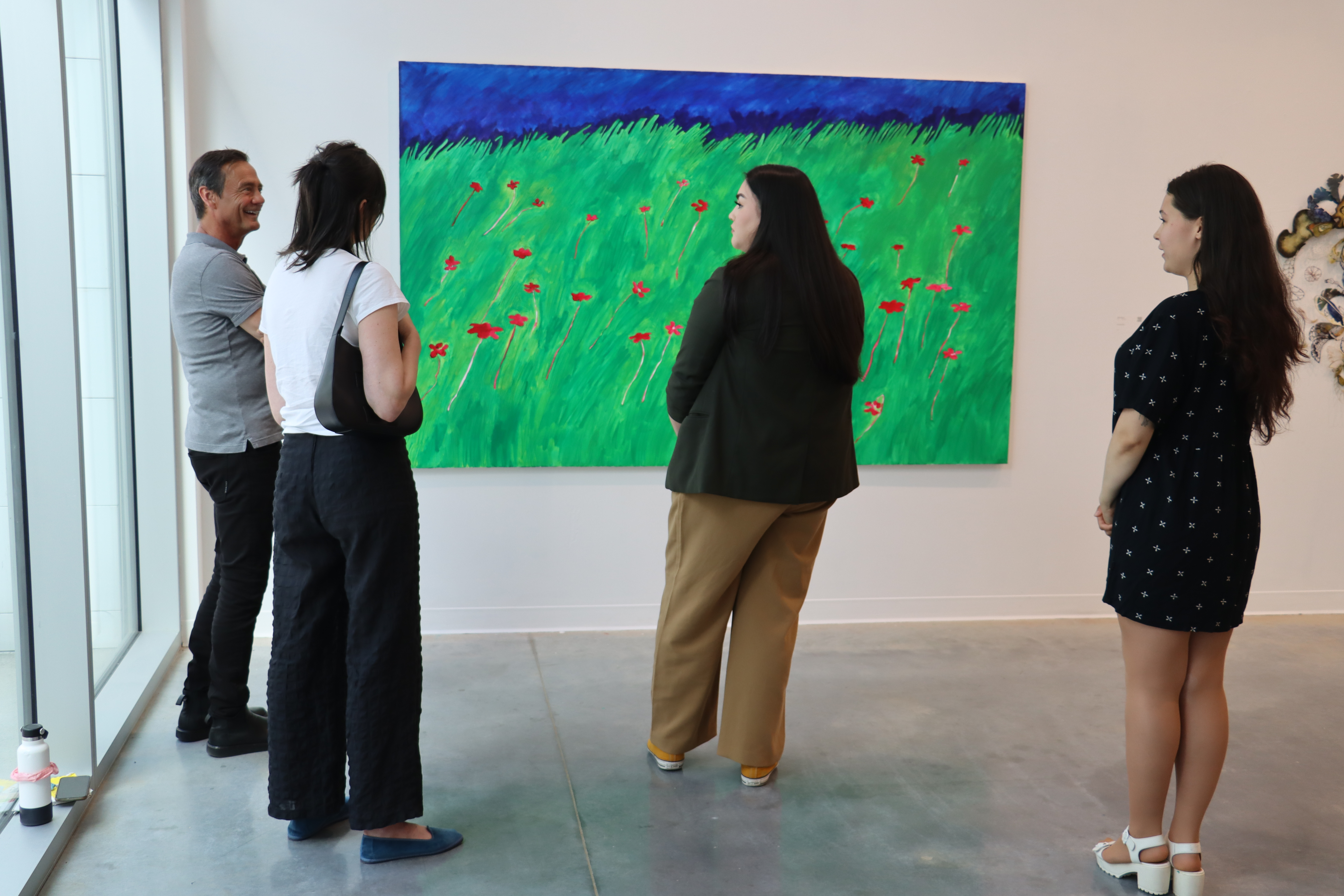 Four people surrounding an artwork with bright green, navy blue and red strokes