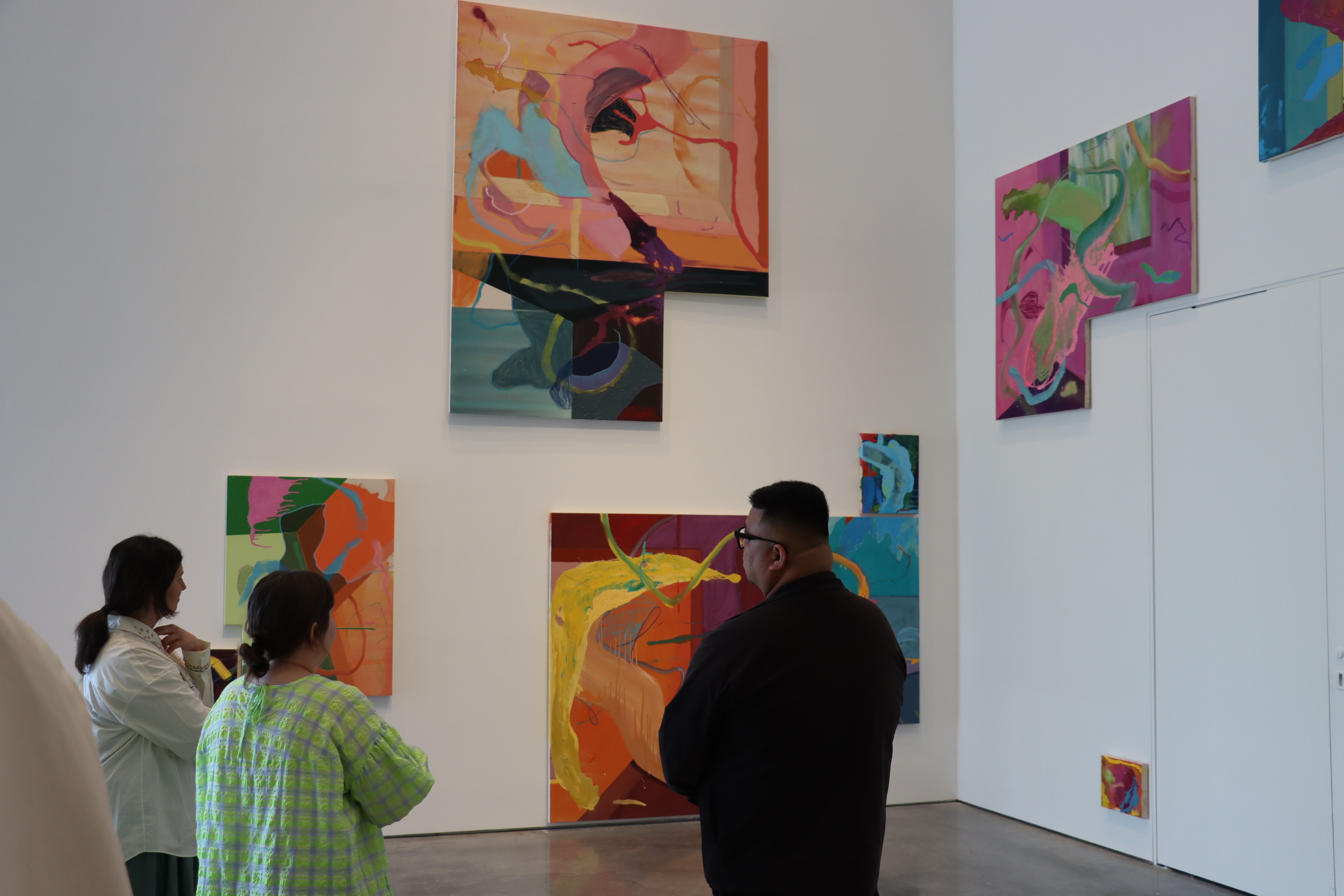 Three people standing in front of vibrant artwork that is cascading upward