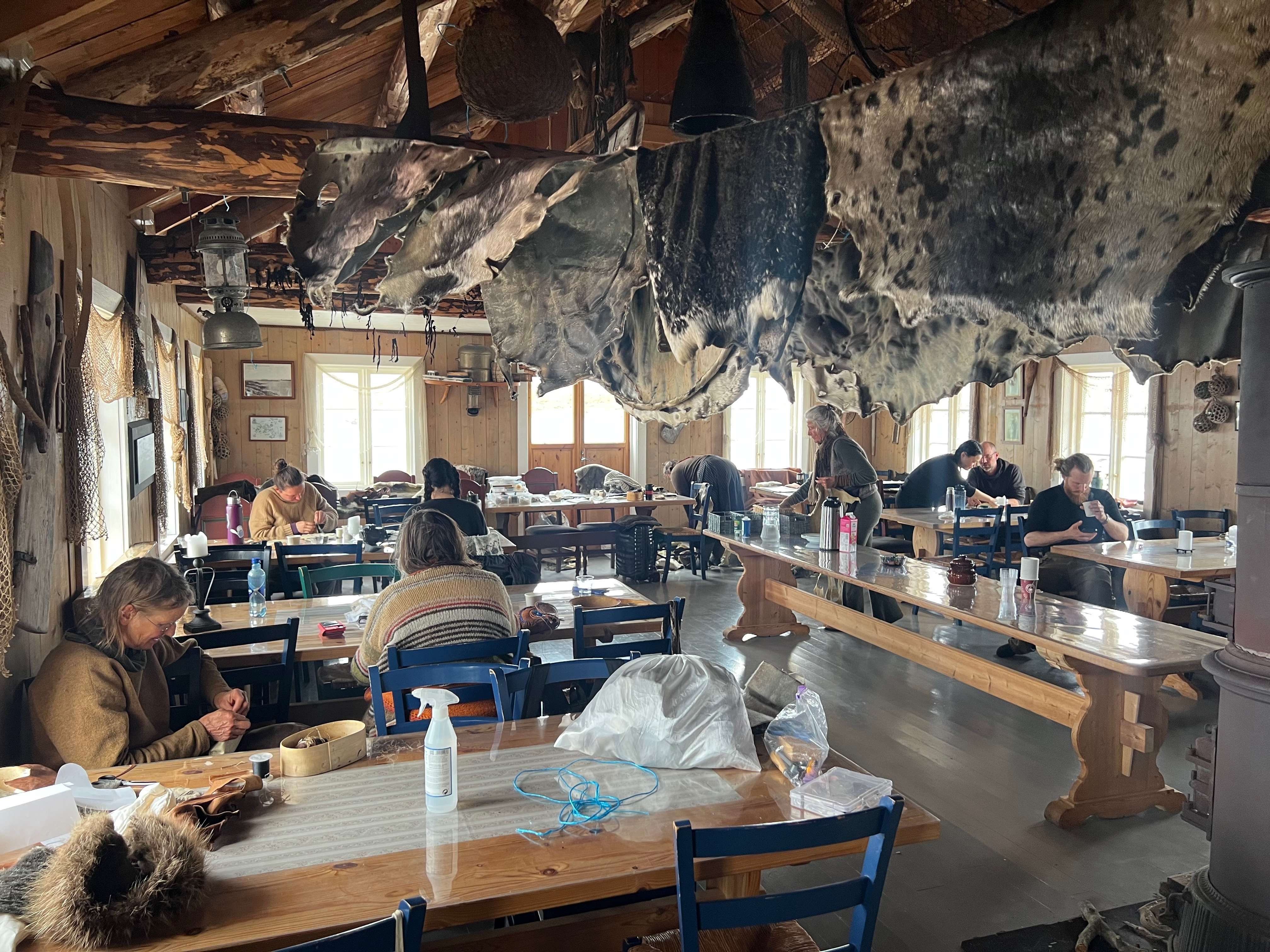 A group of people at tables in a house with seal skin hides hanging above them