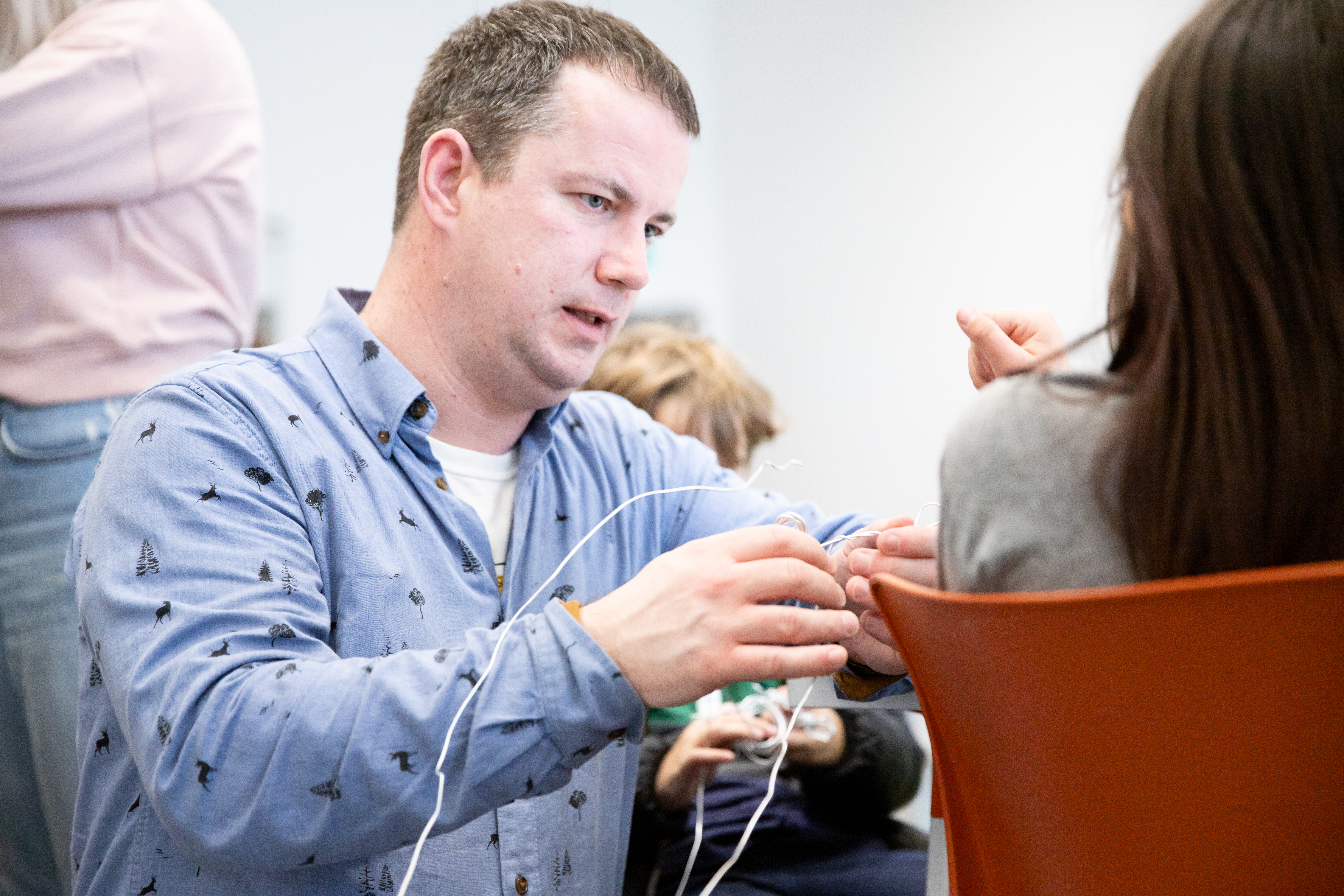A man talking to a student with wires in his hands