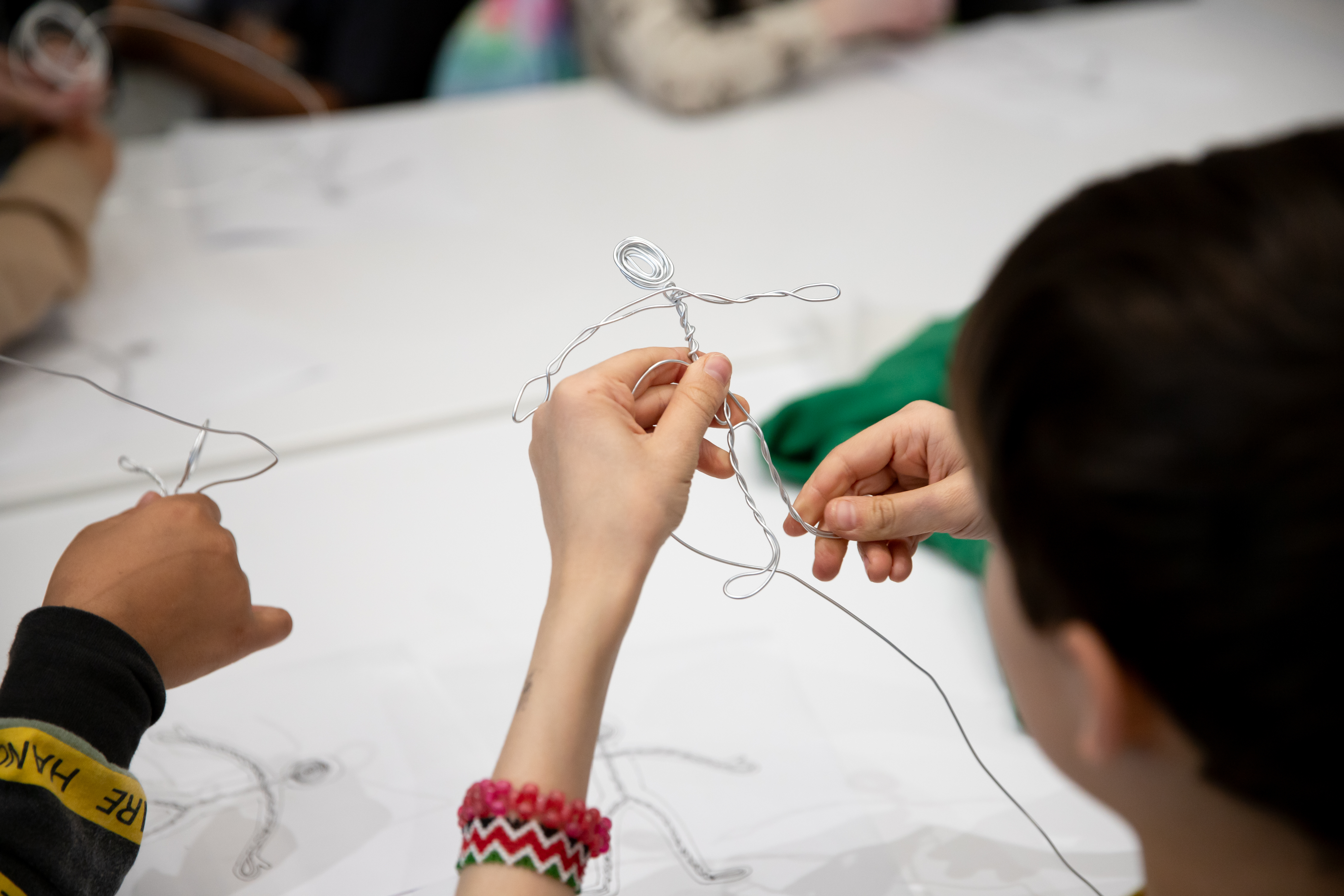 A student is using pliable wire to make a stick figure