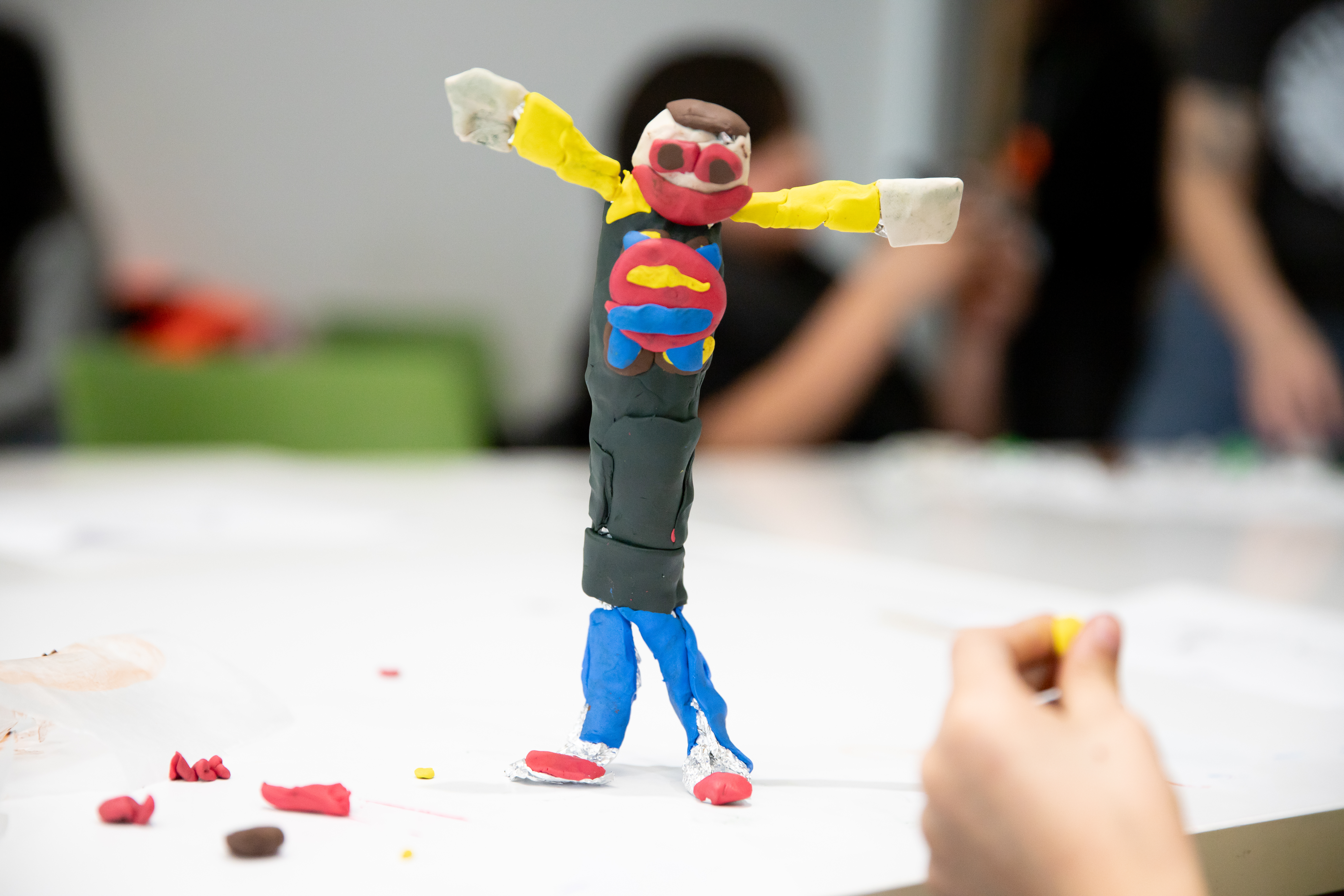 A puppet with its arms out with yellow, red, blue and