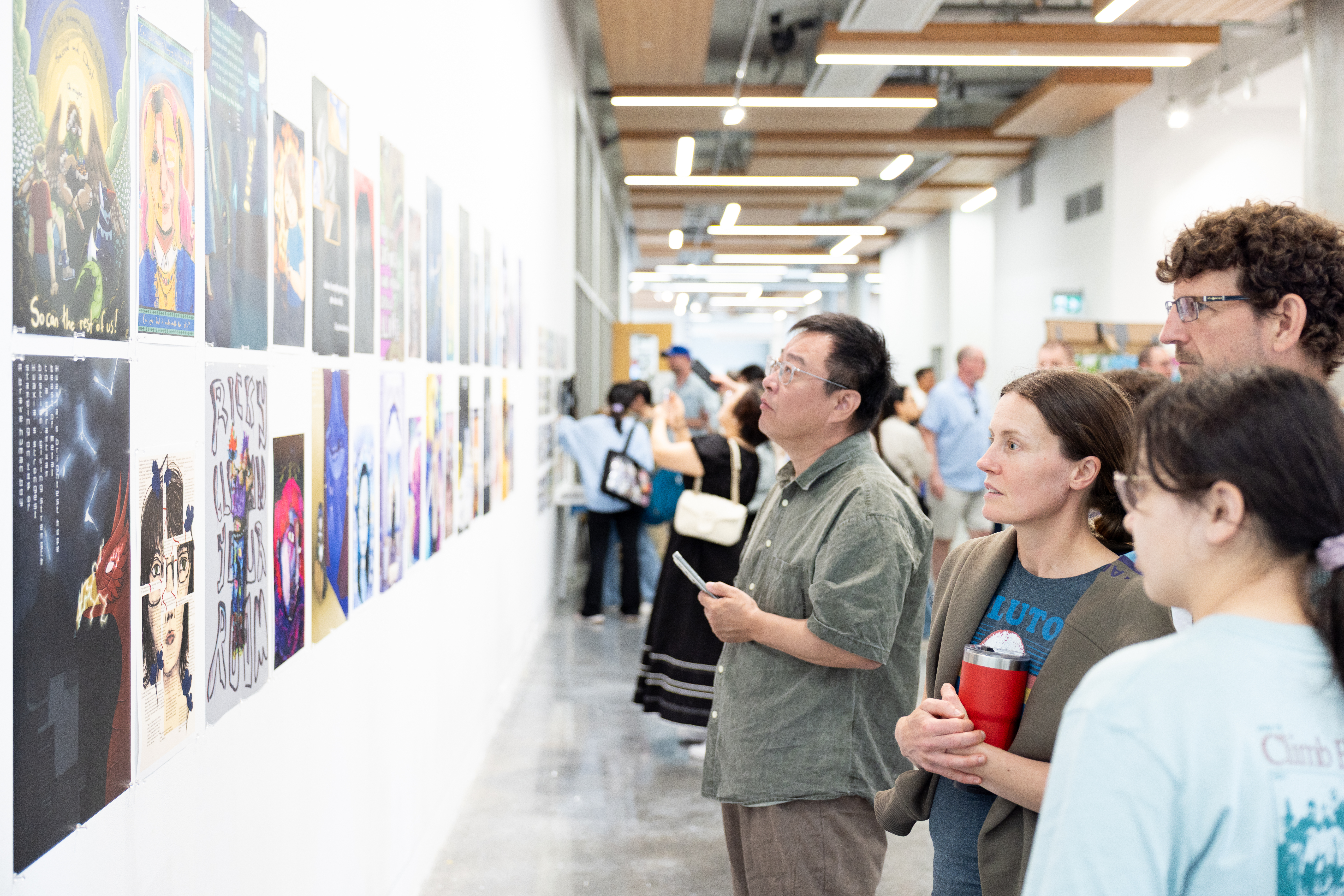 Four people on the left look at a wall full of artworks