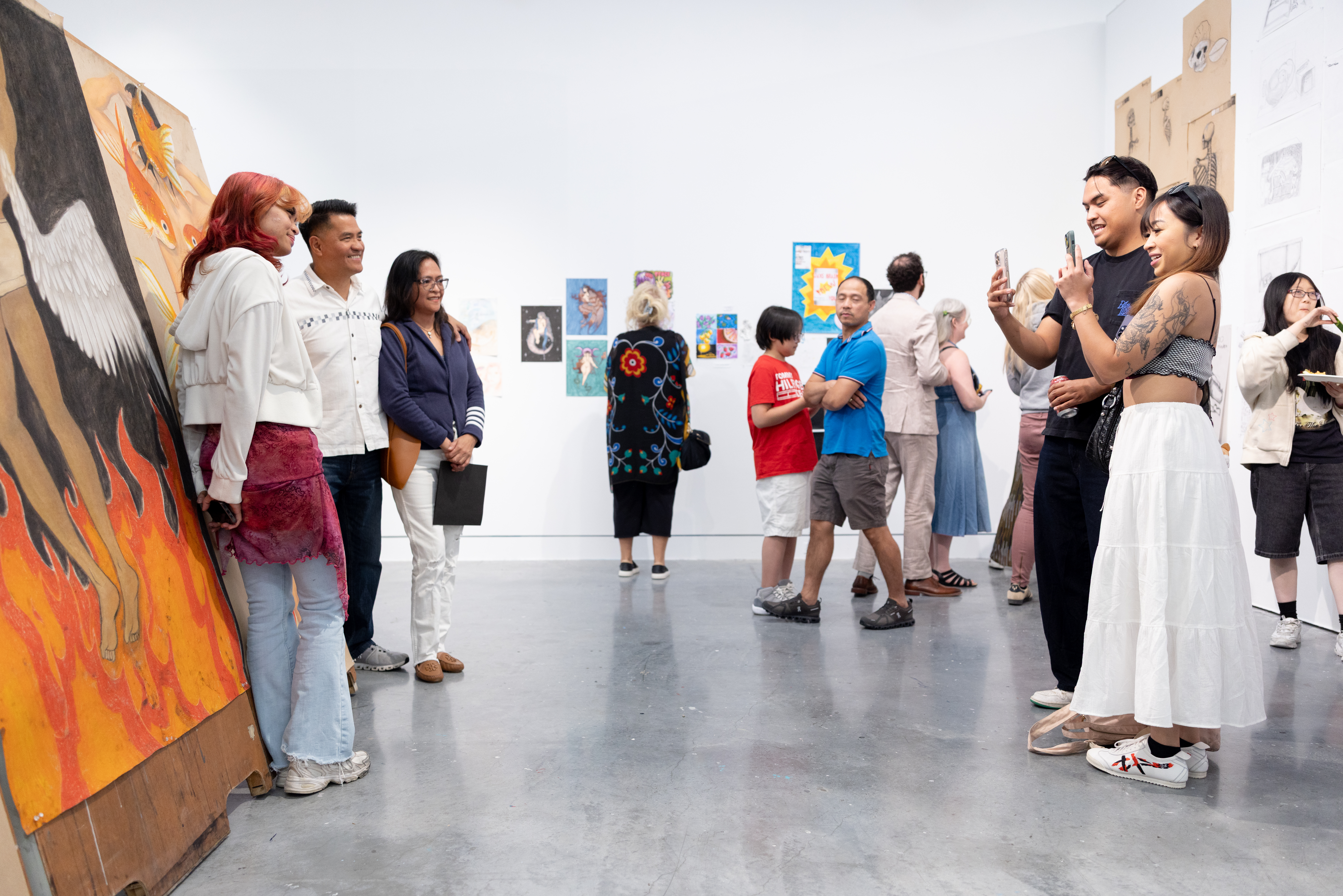 Two people on the right take a photo of an artist and two other people in front of their artwork