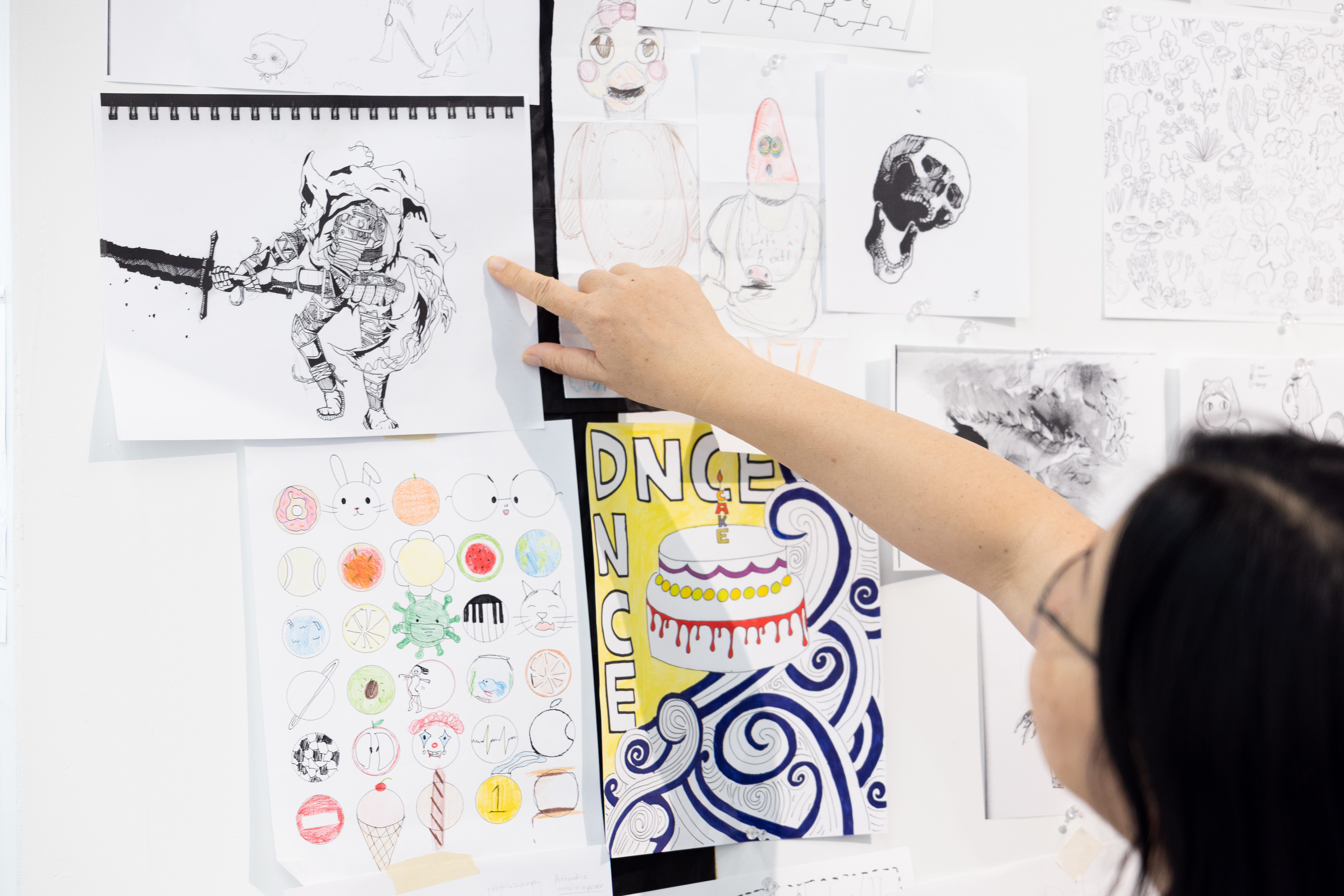Someone in far right points at a drawing on a wall