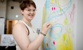student smiling at the camera drawing