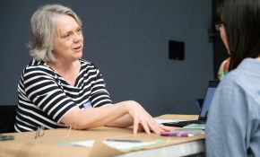 An industry lead chats with a student at a wooden table