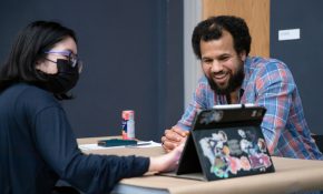 A student and industry lead look at an iPad at a wooden table