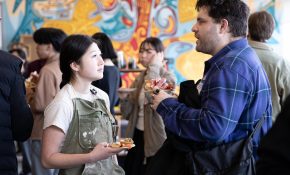 A student and industry lead chat against a colourful background at a mixer