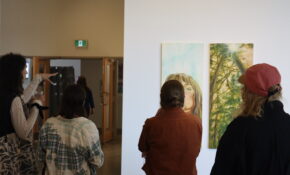 A person pointing at an artwork of a person, alongside three other people