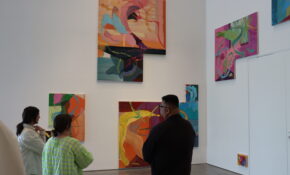 Three people standing in front of vibrant artwork that is cascading upward