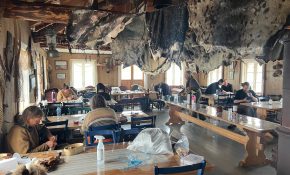 A group of people at tables in a house with seal skin hides hanging above them
