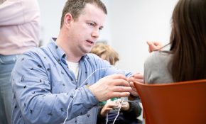 A man talking to a student with wires in his hands