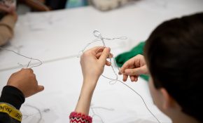 A student is using pliable wire to make a stick figure