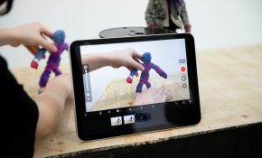 A student moves a blue-purple figure into frame with an iPad in the foreground