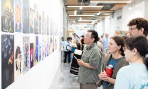 Four people on the left look at a wall full of artworks