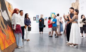 Two people on the right take a photo of an artist and two other people in front of their artwork