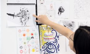 Someone in far right points at a drawing on a wall