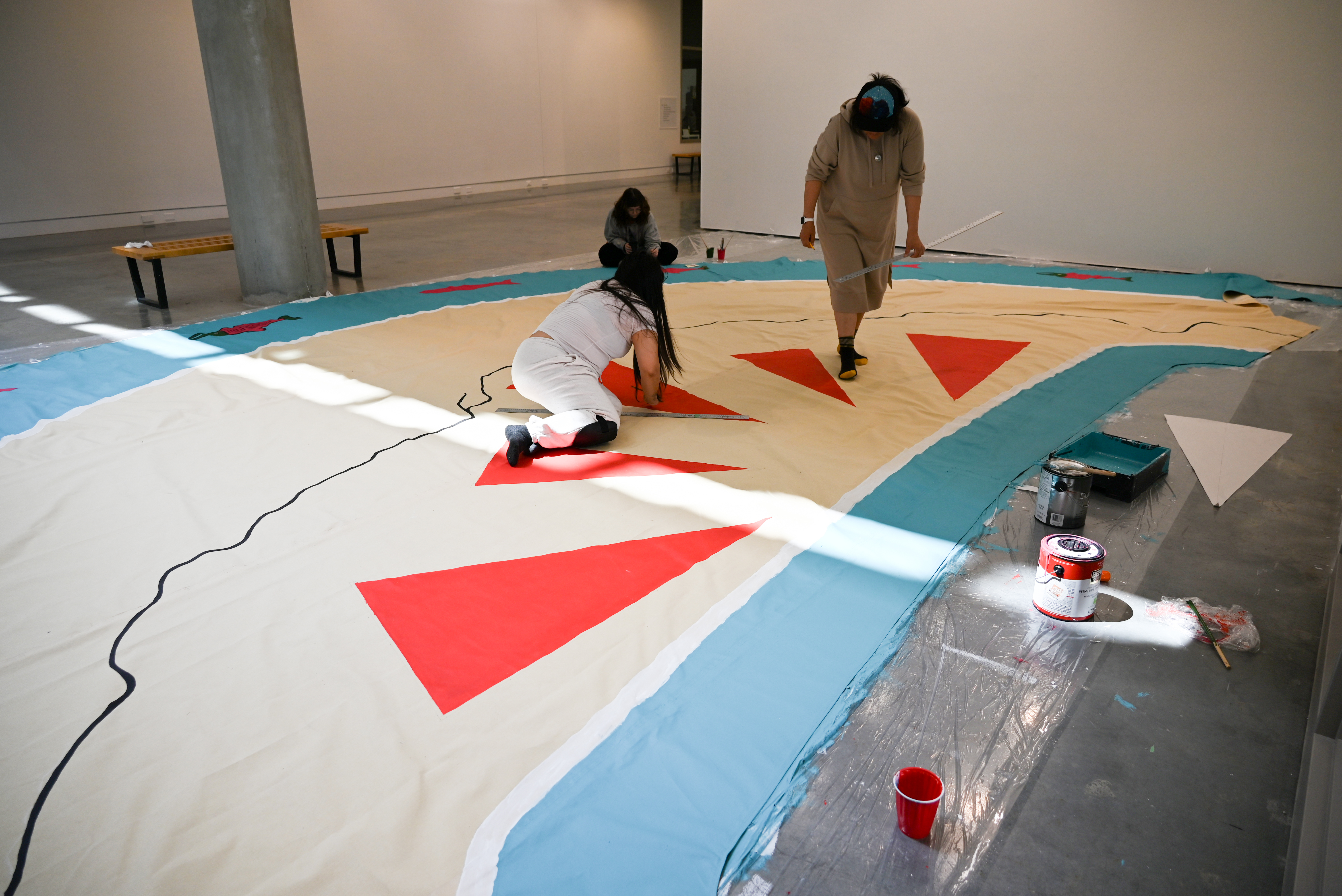(From L): Alysha Johnny Hawkins, Isabelle Jarman and Jennifer Mitchell paint the canvas covering. (Photo by Sydney Pascal / courtesy the AGP)