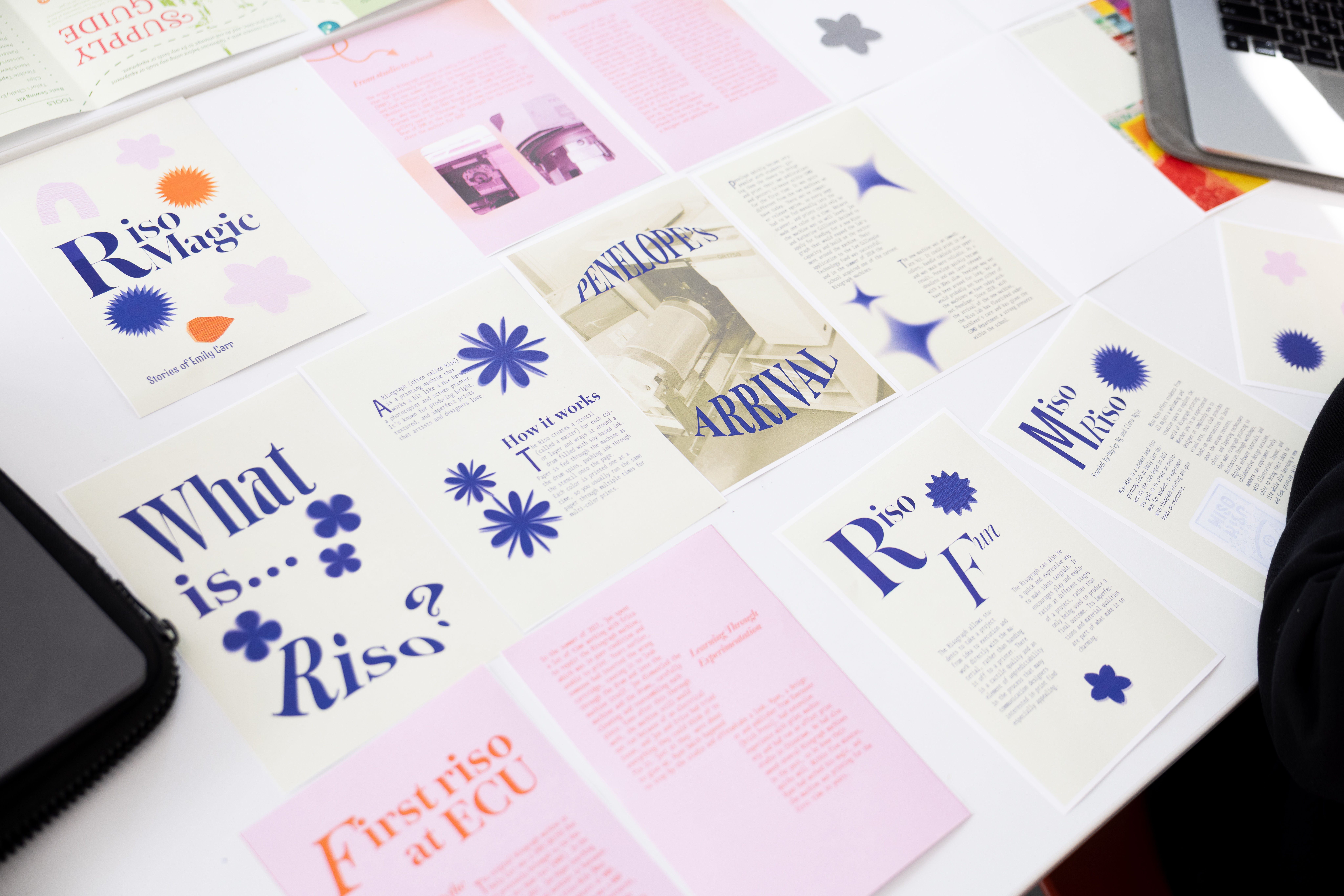 Pieces of paper bearing colourful text and graphics are spread across a table.