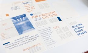 Pieces of paper bearing colourful text and graphics are spread across a table.