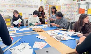 People work with printed publications around a table in a studio bearing colourful risograph prints on the walls.